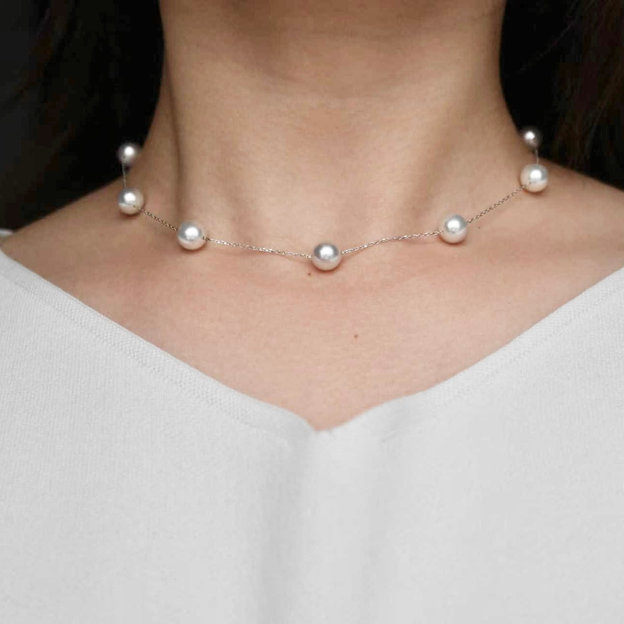 Elegant Akoya pearl necklace with delicate chain, showcasing lustrous pearls on a model.