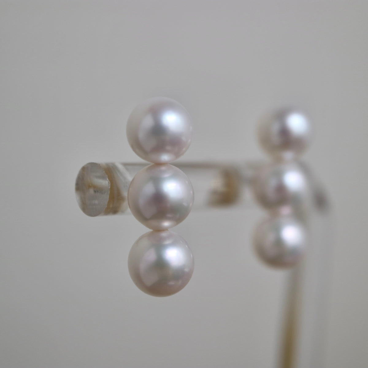 Handmade Japanese Akoya pearl earrings with lustrous white pearls, displayed on a stand