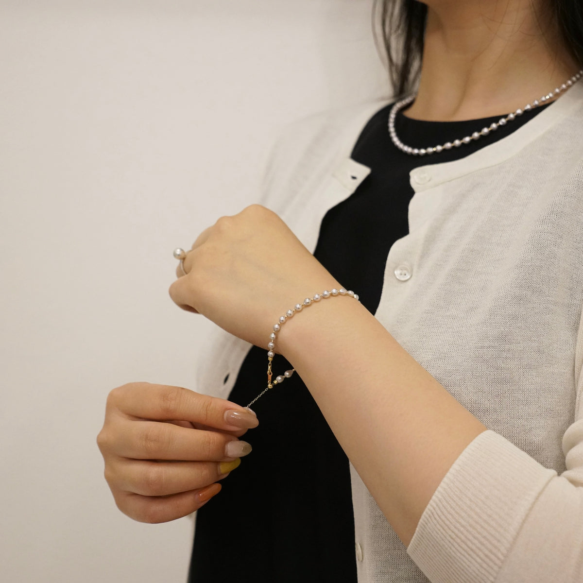 alt
白いカーディガンを着た女性が身につけた、上品なアコヤ真珠のブレスレットとネックレスのセット