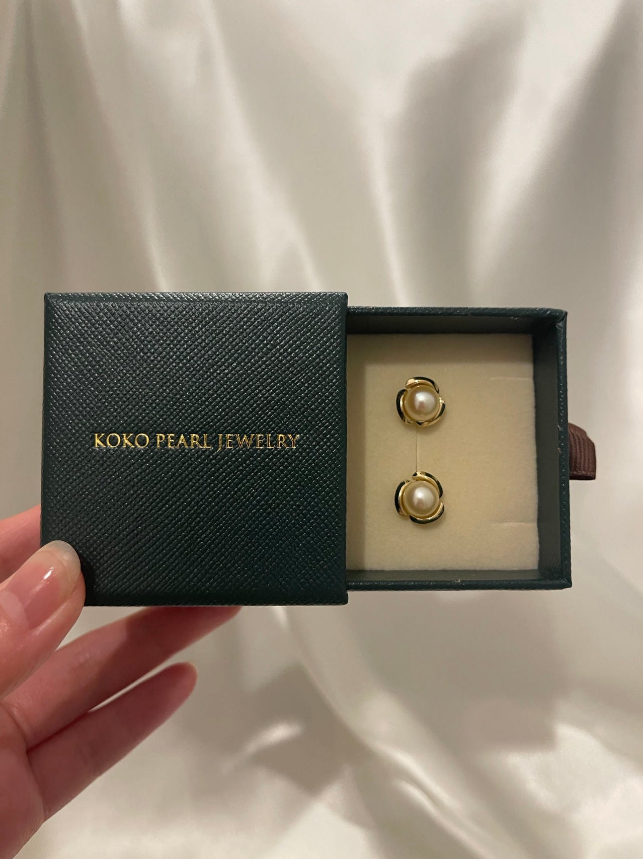 Pair of white Akoya pearl earrings in a dark green KOKO PEARL JEWELRY gift box.