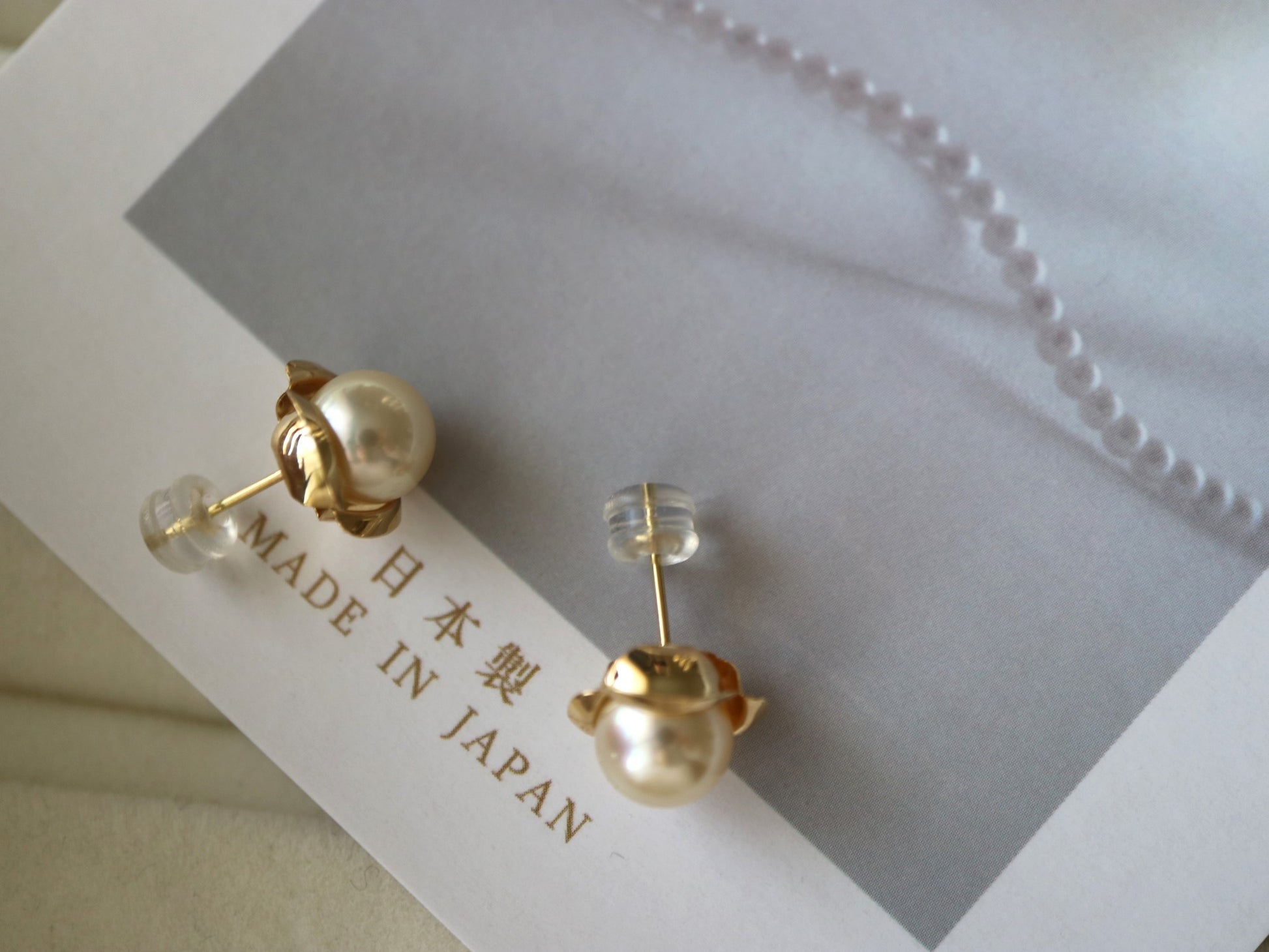 Handmade Japanese Akoya pearl stud earrings with gold settings on a 'MADE IN JAPAN' card.