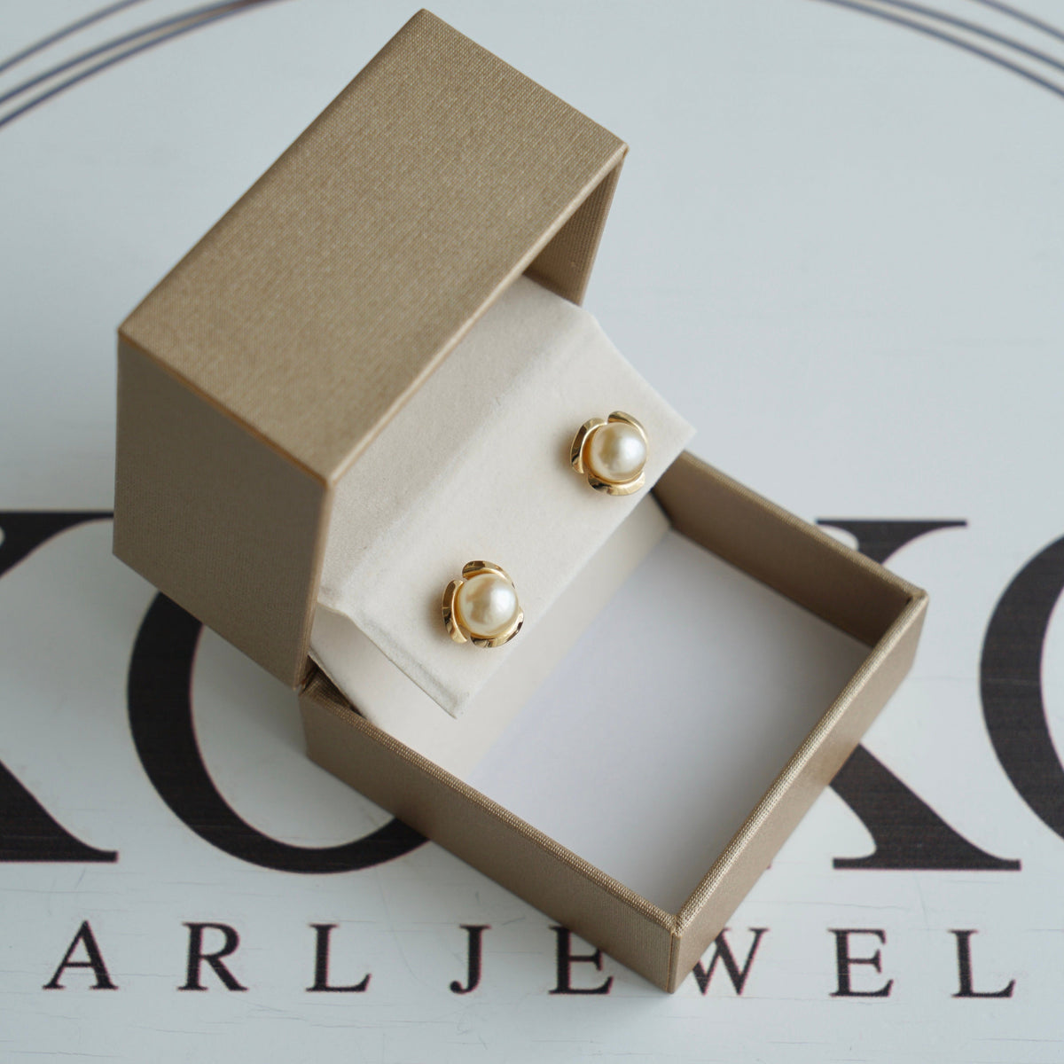 Pair of white Akoya pearl stud earrings in a gold-tone box.