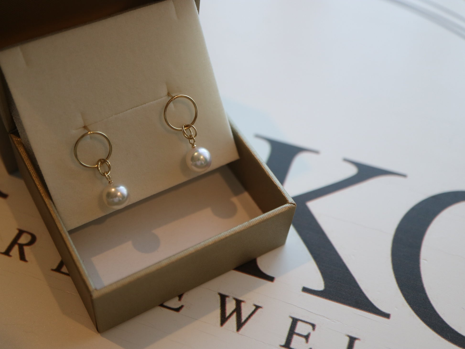 Pair of Akoya pearl drop earrings with gold hoop studs in a jewelry box