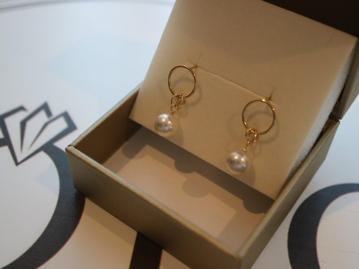 Gold hoop earrings with dangling Akoya pearls in a jewelry gift box