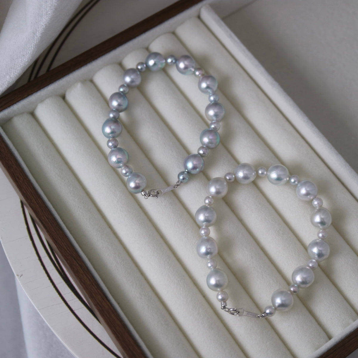 Handmade Japanese Akoya pearl necklace with iridescent luster, displayed in a luxury jewelry box.