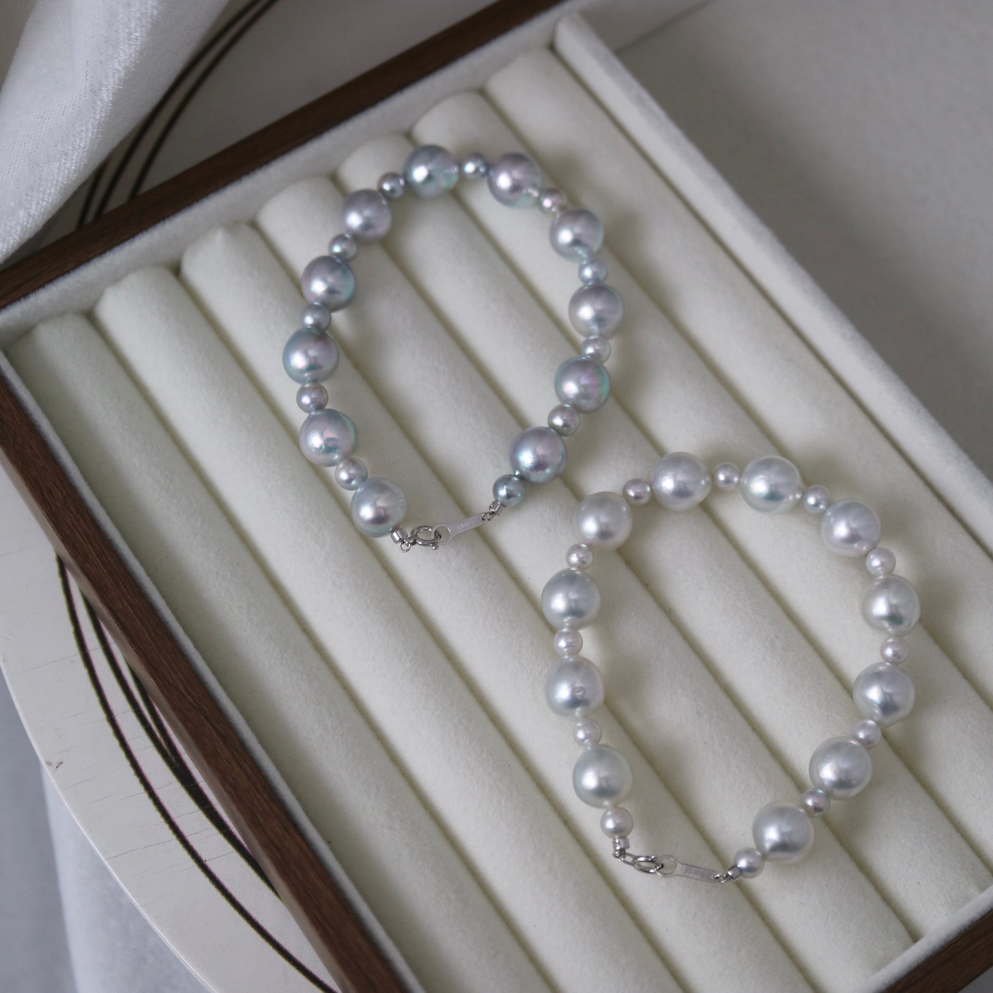 Handmade Japanese Akoya pearl necklace with iridescent luster, displayed in a luxury jewelry box.