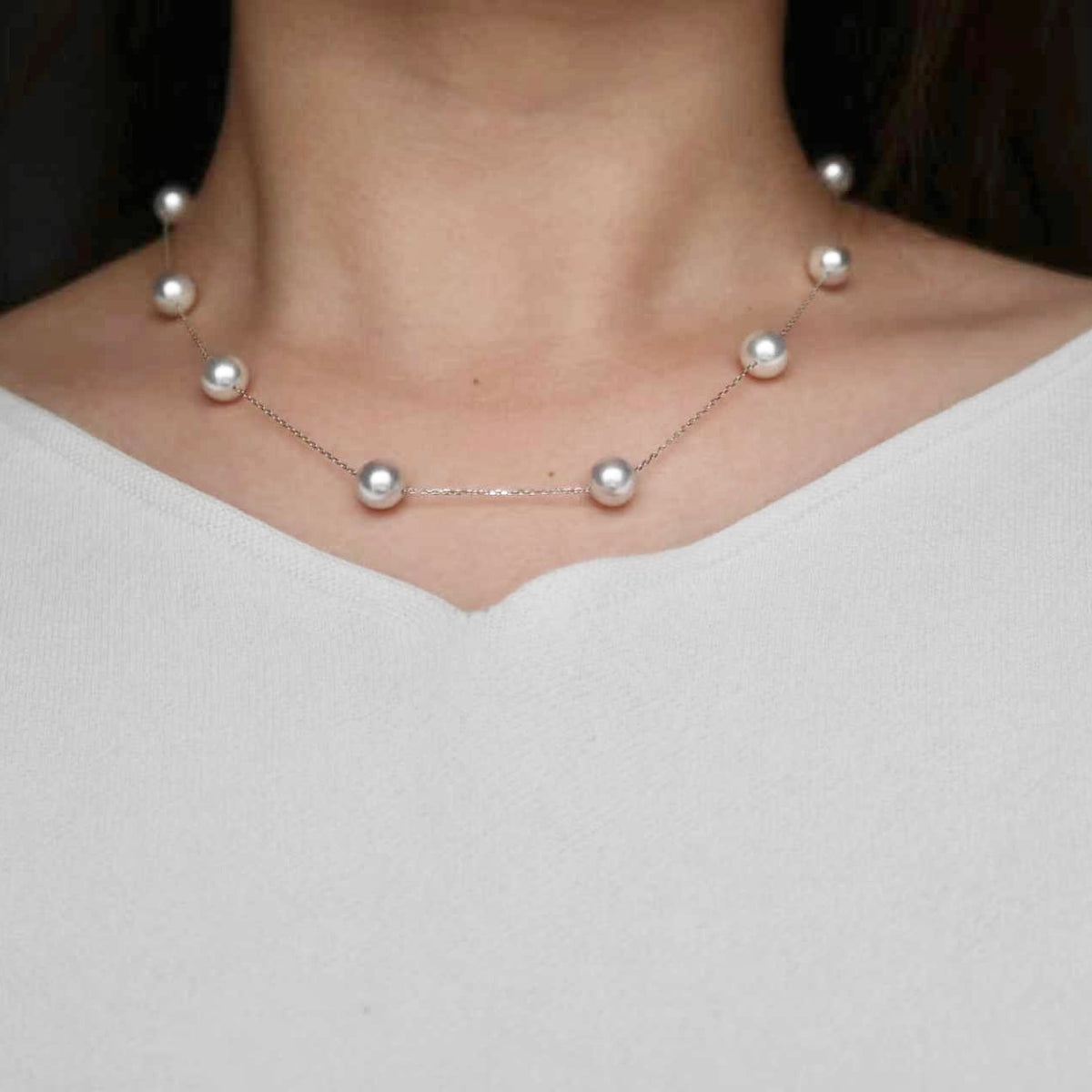 Elegant Akoya pearl necklace with delicate chain, showcasing lustrous seawater pearls on a model.
