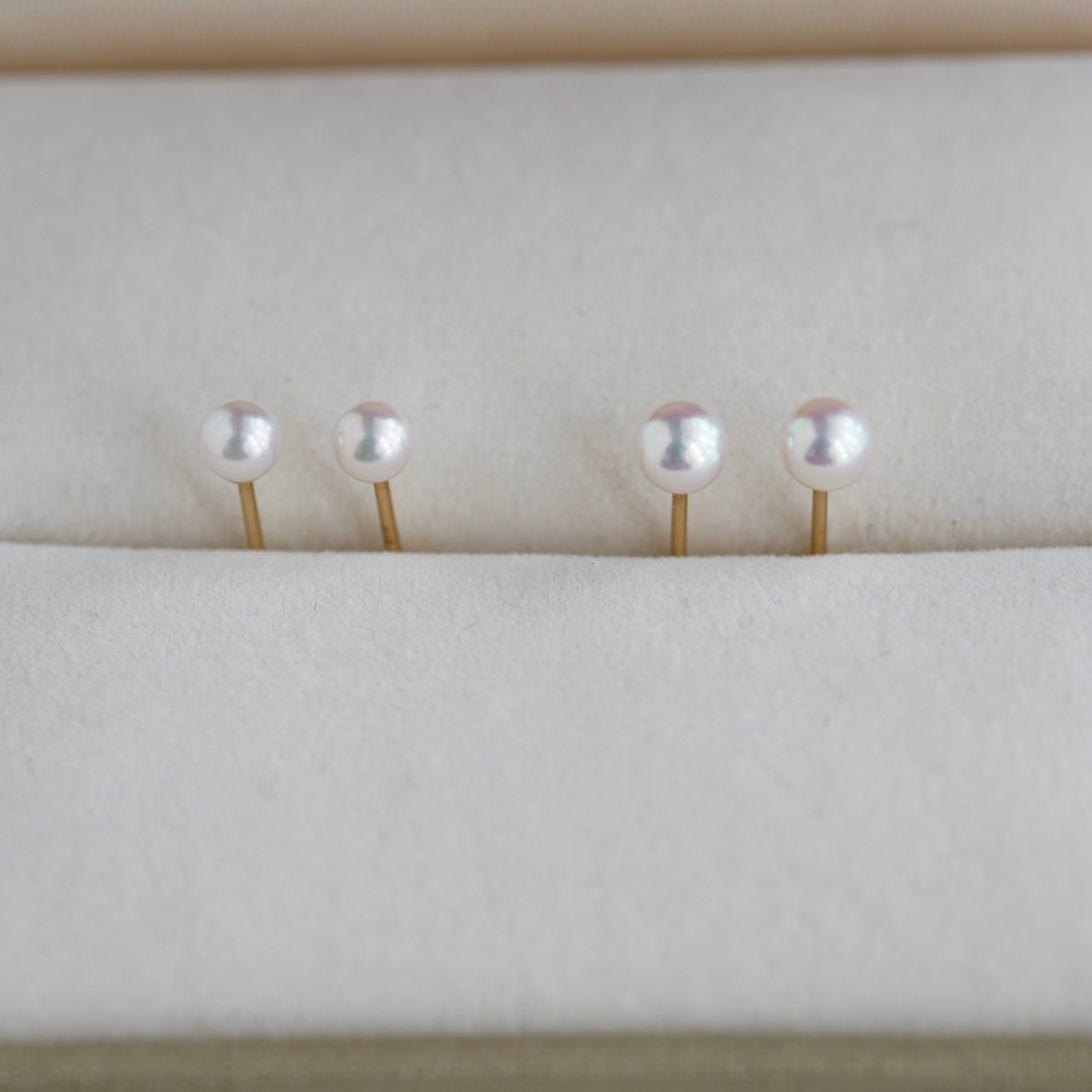 Handmade Akoya pearl earrings with gold posts, displayed on soft white fabric