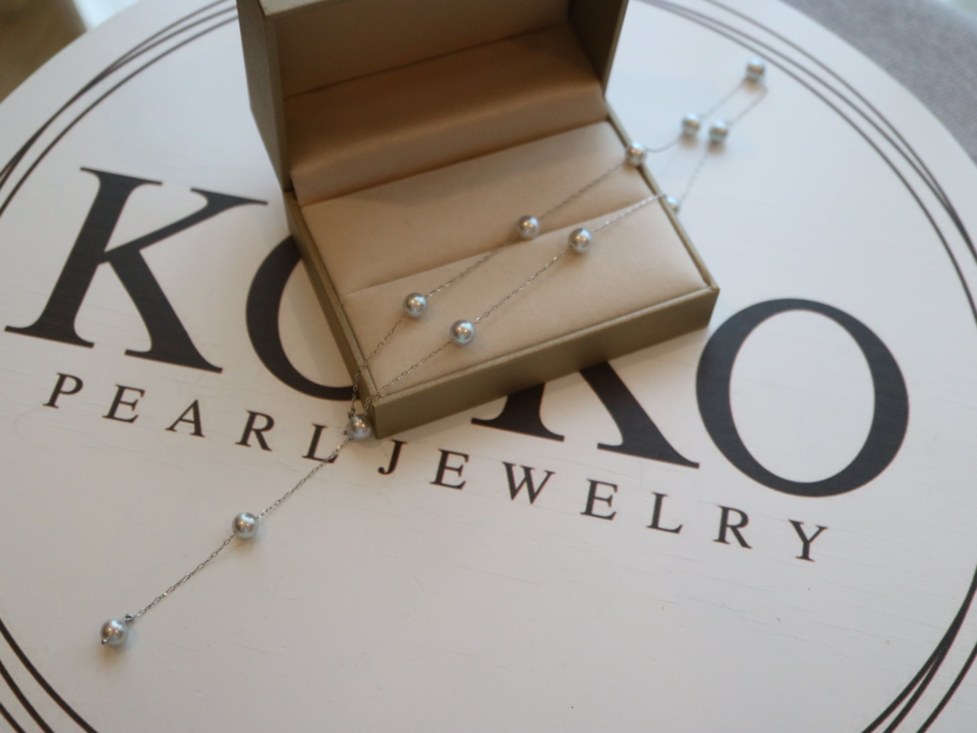 手工日本Akoya珍珠项链，配银链，放置在KOKO Pearl Jewelry表面的礼盒中展示