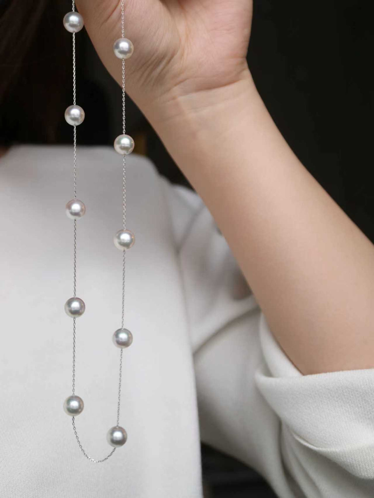Handheld Japanese Akoya pearl necklace with lustrous seawater pearls on delicate chain