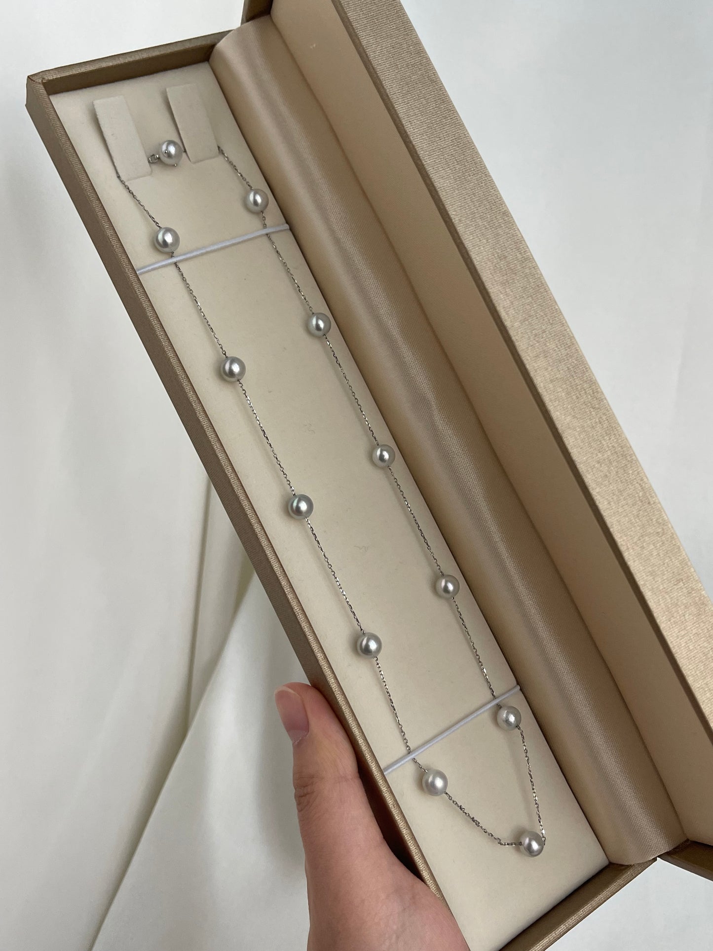 Elegant Japanese Akoya 珍珠项链和耳钉套装，置于奢华礼盒中，细链上点缀着光泽莹润的海水珍珠。