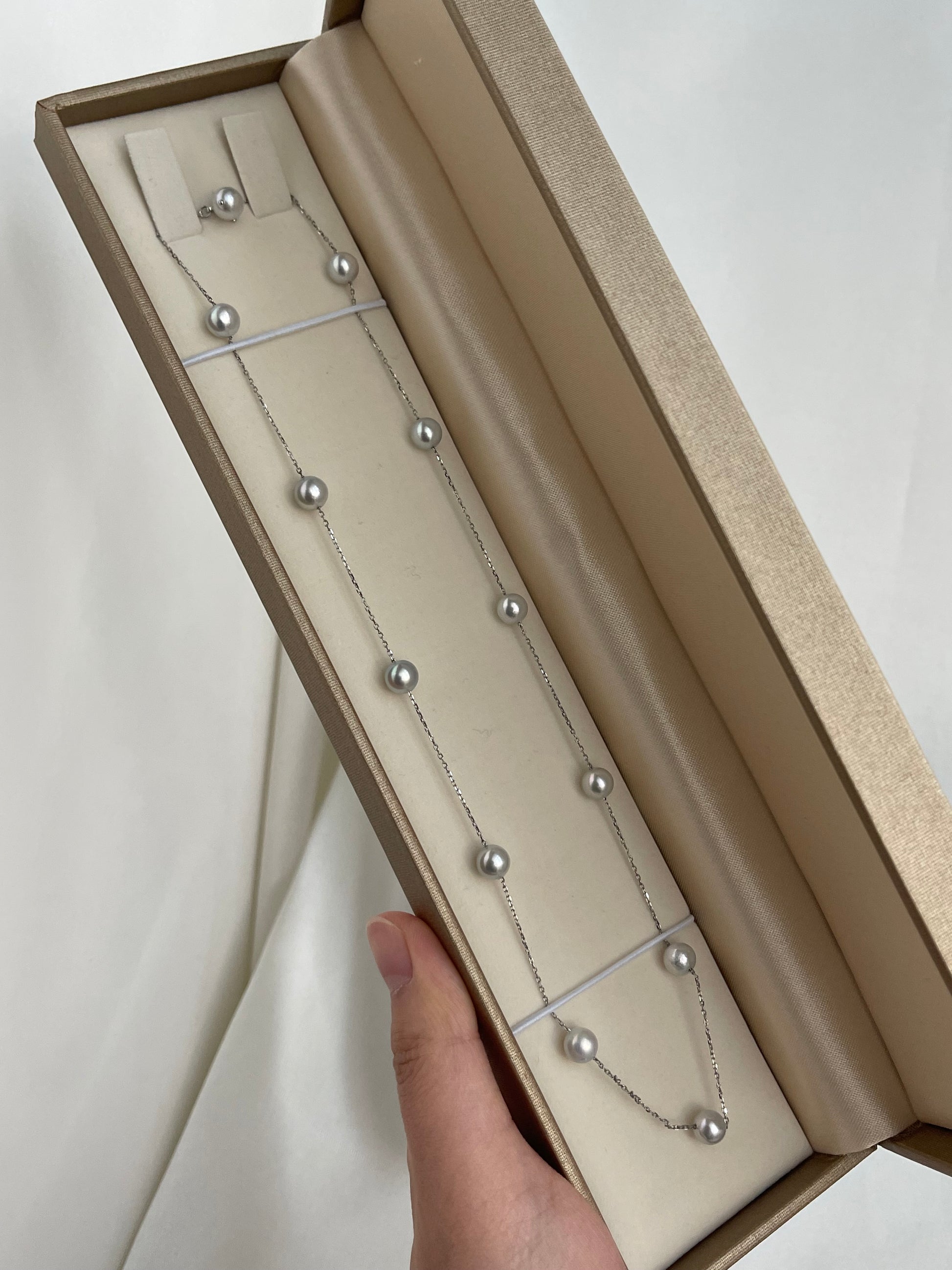 Elegant Japanese Akoya 珍珠项链和耳钉套装，置于奢华礼盒中，细链上点缀着光泽莹润的海水珍珠。