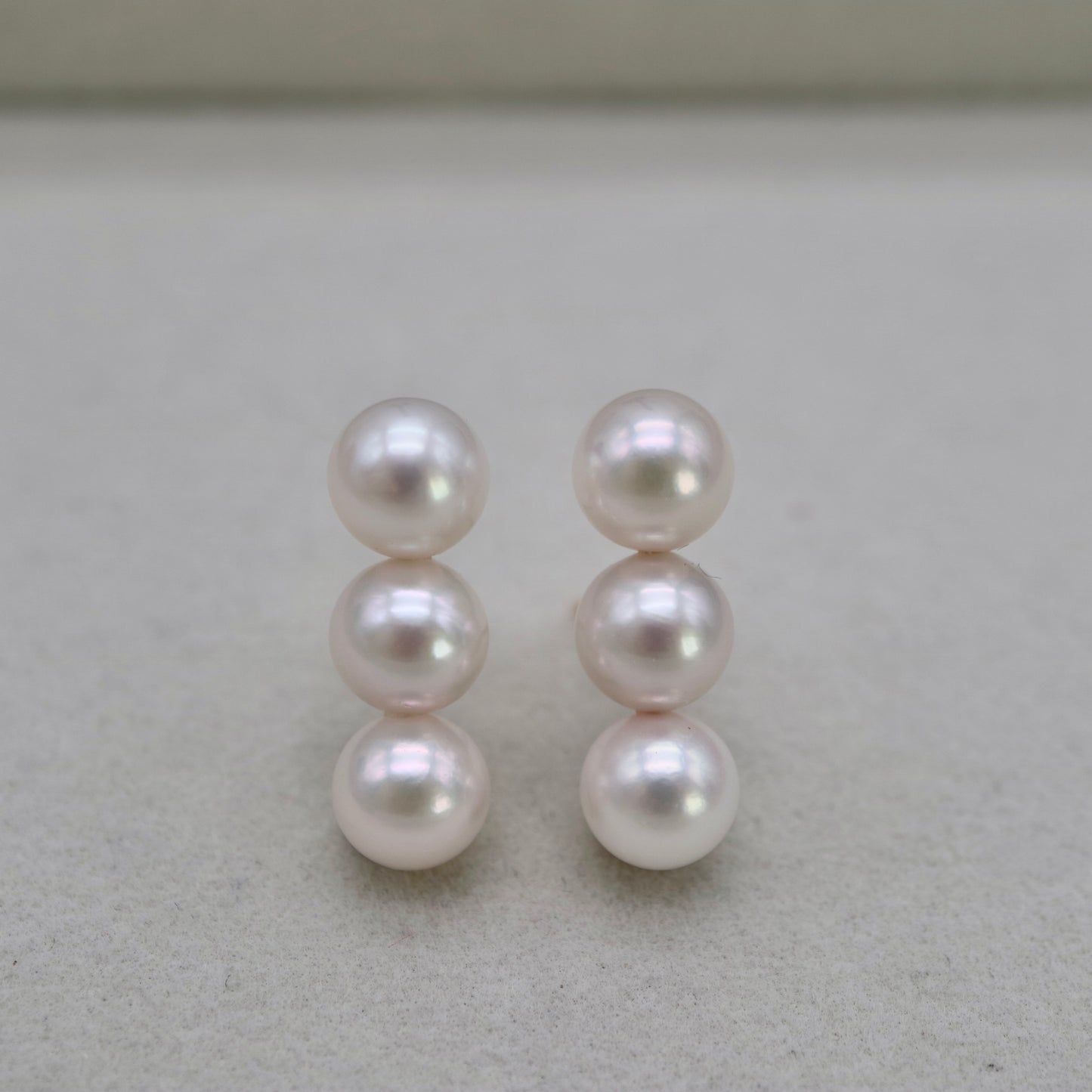 Handmade Japanese Akoya pearl earrings, three pearls each, lustrous white, unedited photo