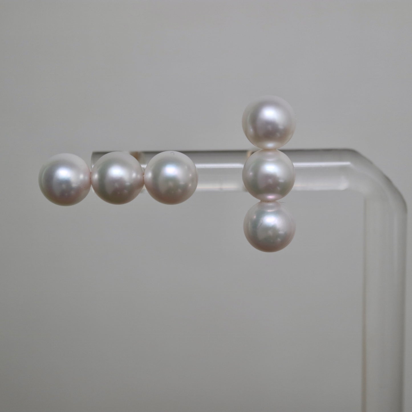 Handmade Japanese Akoya pearl earrings, lustrous white pearls on clear display stand
