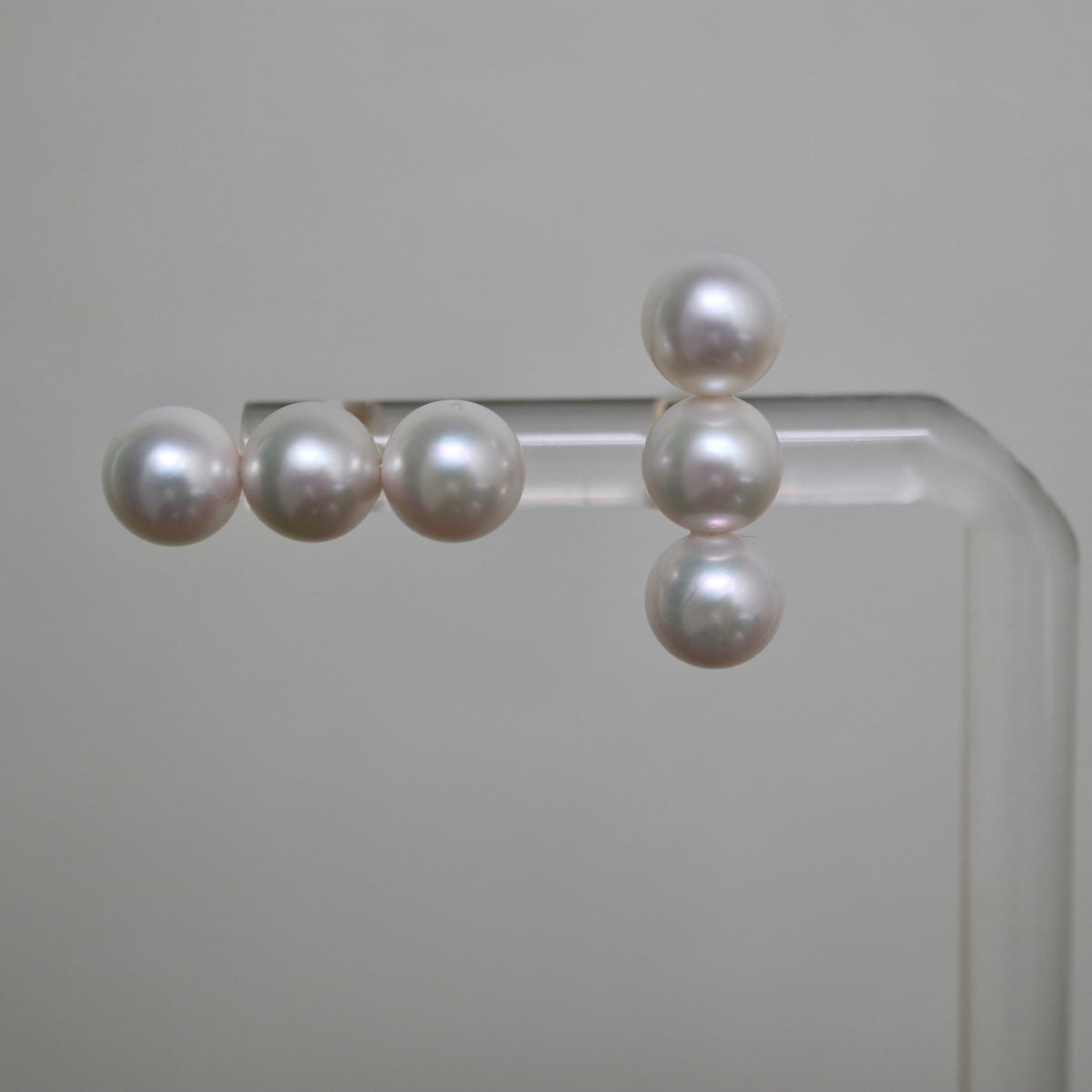 Handmade Japanese Akoya pearl earrings, lustrous white pearls on clear display stand