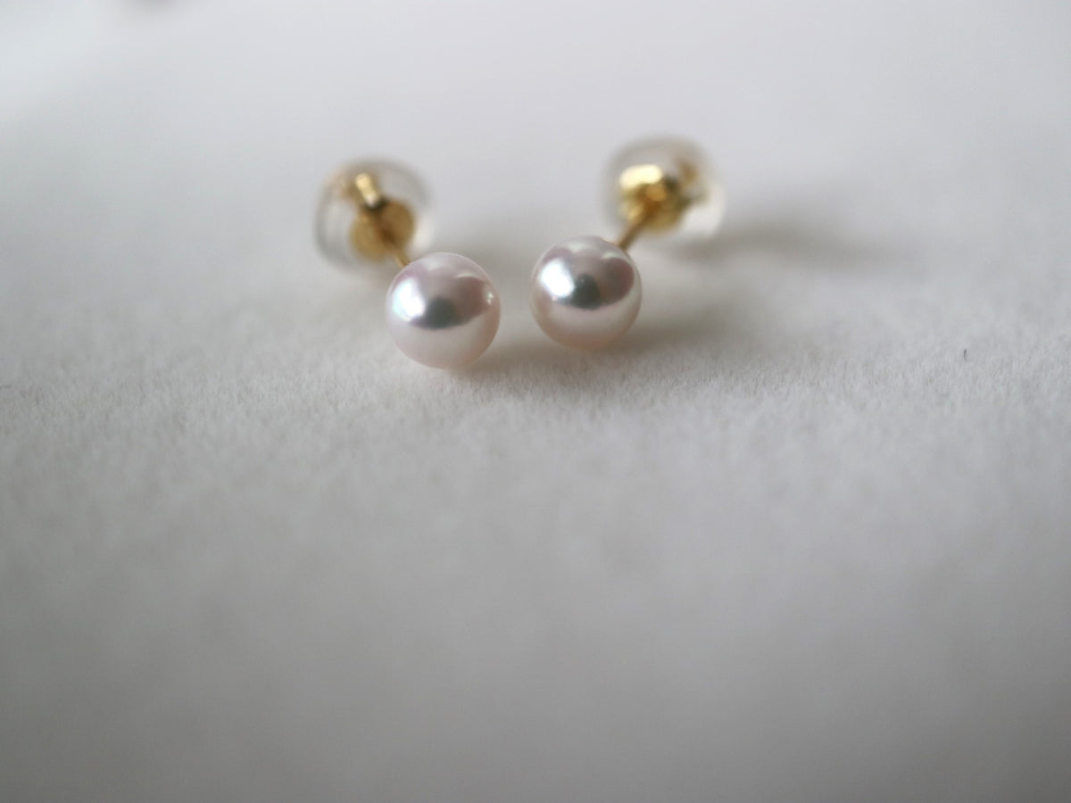 Handmade Japanese Akoya pearl stud earrings with gold posts, showcasing lustrous seawater pearls on soft white background