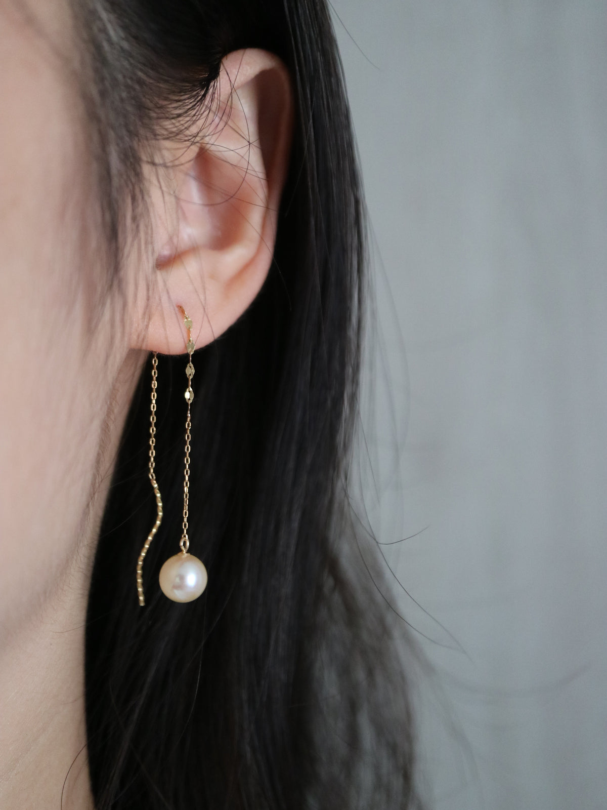 KOKO PEARL JEWELRYの上品な手作りゴールドチェーンのアコヤ真珠イヤリングを着けた女性の耳のクローズアップ