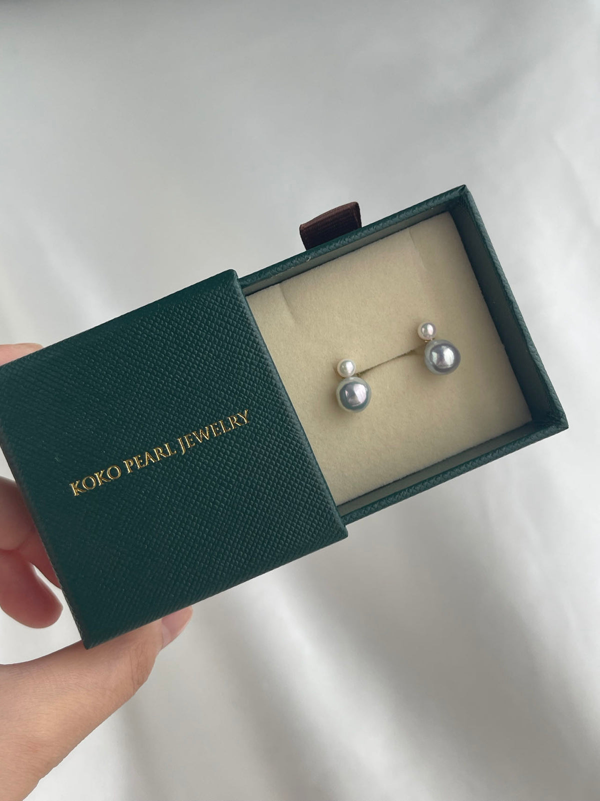Pair of grey Akoya pearl stud earrings in a green KOKO PEARL JEWELRY gift box