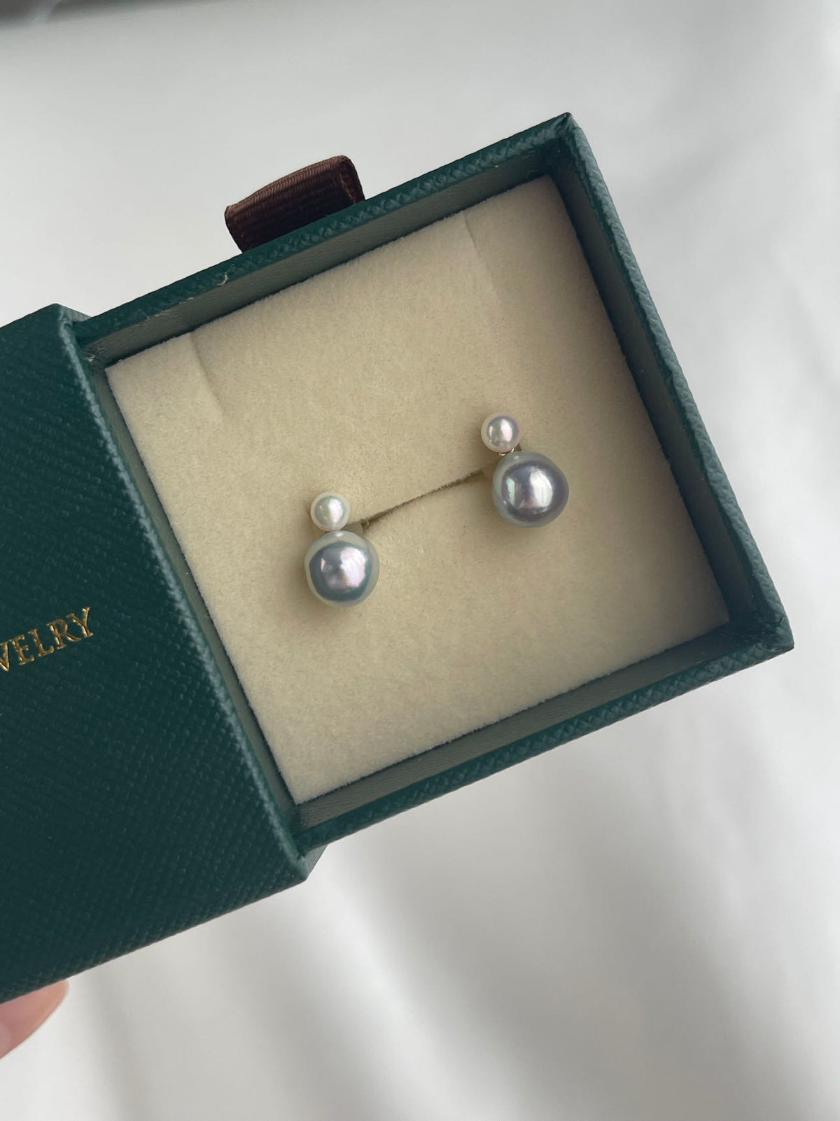 Pair of grey Akoya pearl stud earrings in a dark green jewelry box