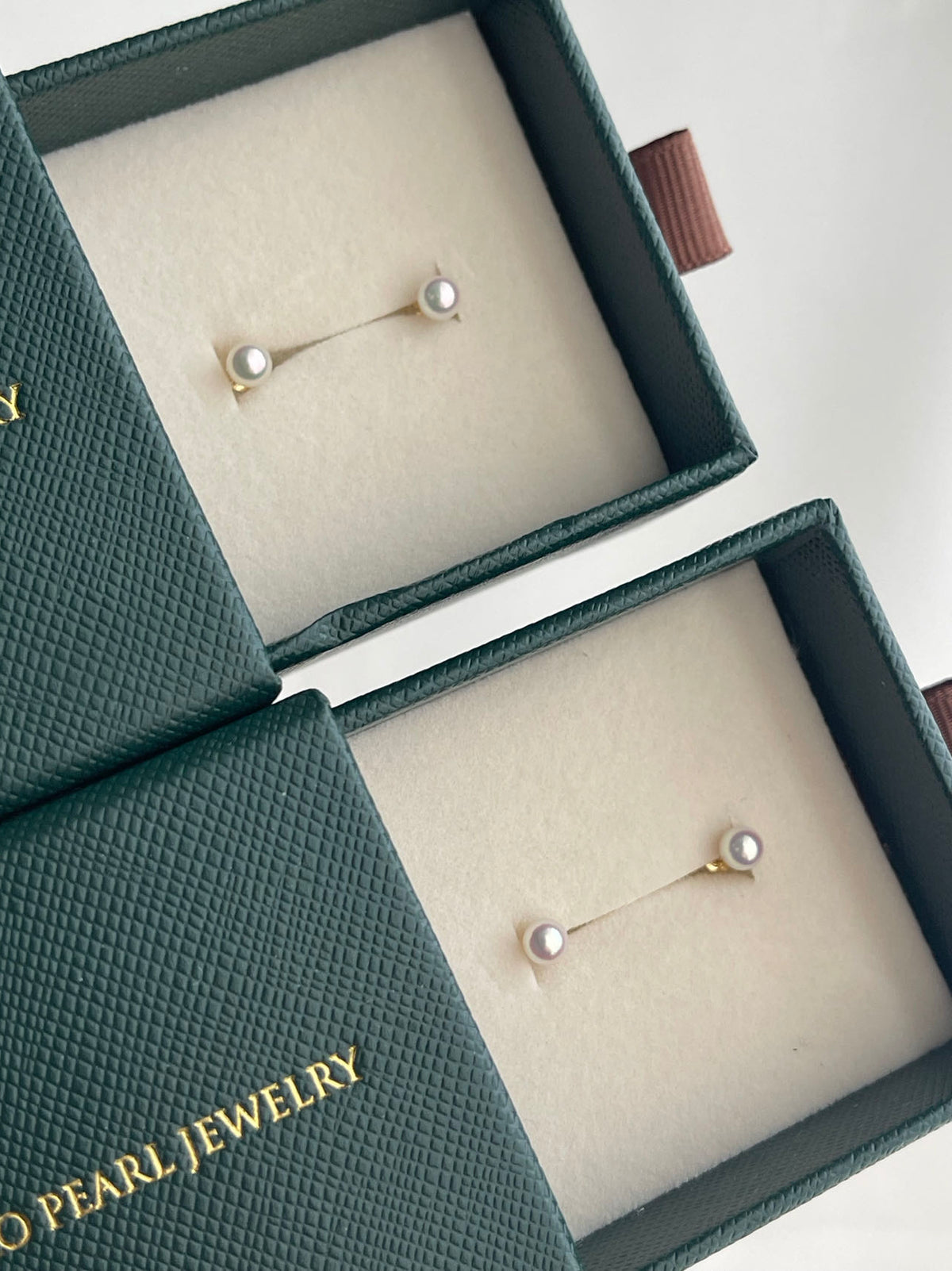 Handmade Japanese Akoya pearl stud earrings in luxury green boxes, showcasing lustrous seawater pearls
